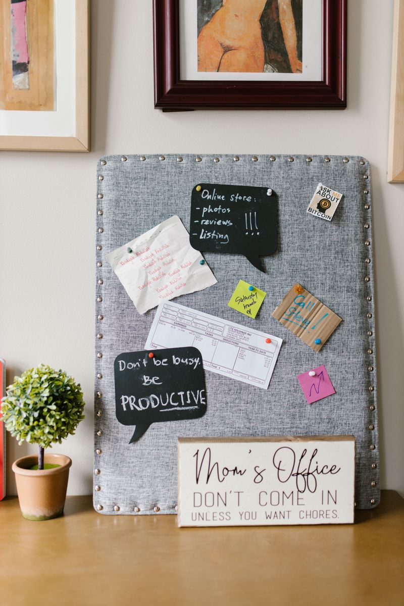 A family of four reviewing a handwritten grocery list at a kitchen table with a laptop open beside them.